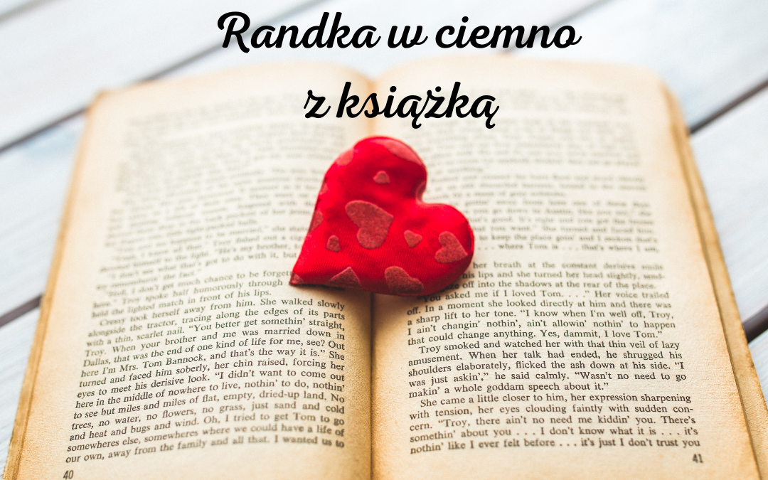 Obrazek wyróżniający do zabawy Randka w Ciemno z Książką. Na zdjęciu jest otwarta książka i leżące na niej czerwone serduszko