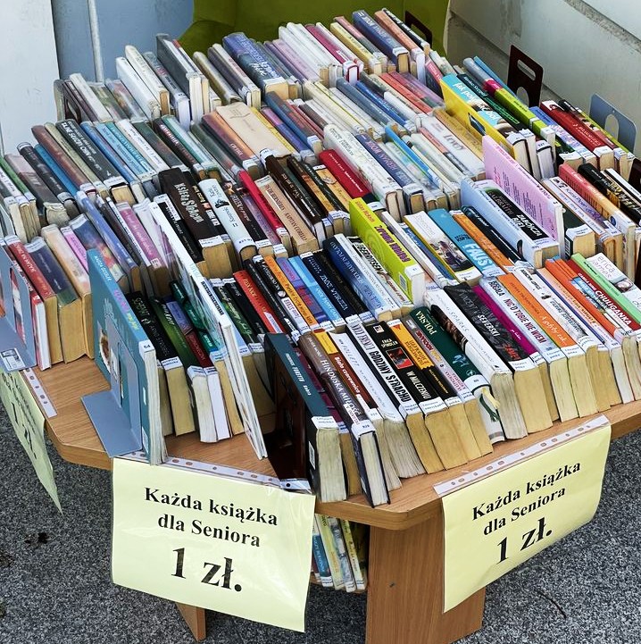 zdjęcie przedstawiające wystawę książek używanych na stole na dole napis na kartce każda książka dla seniora 1 zł.