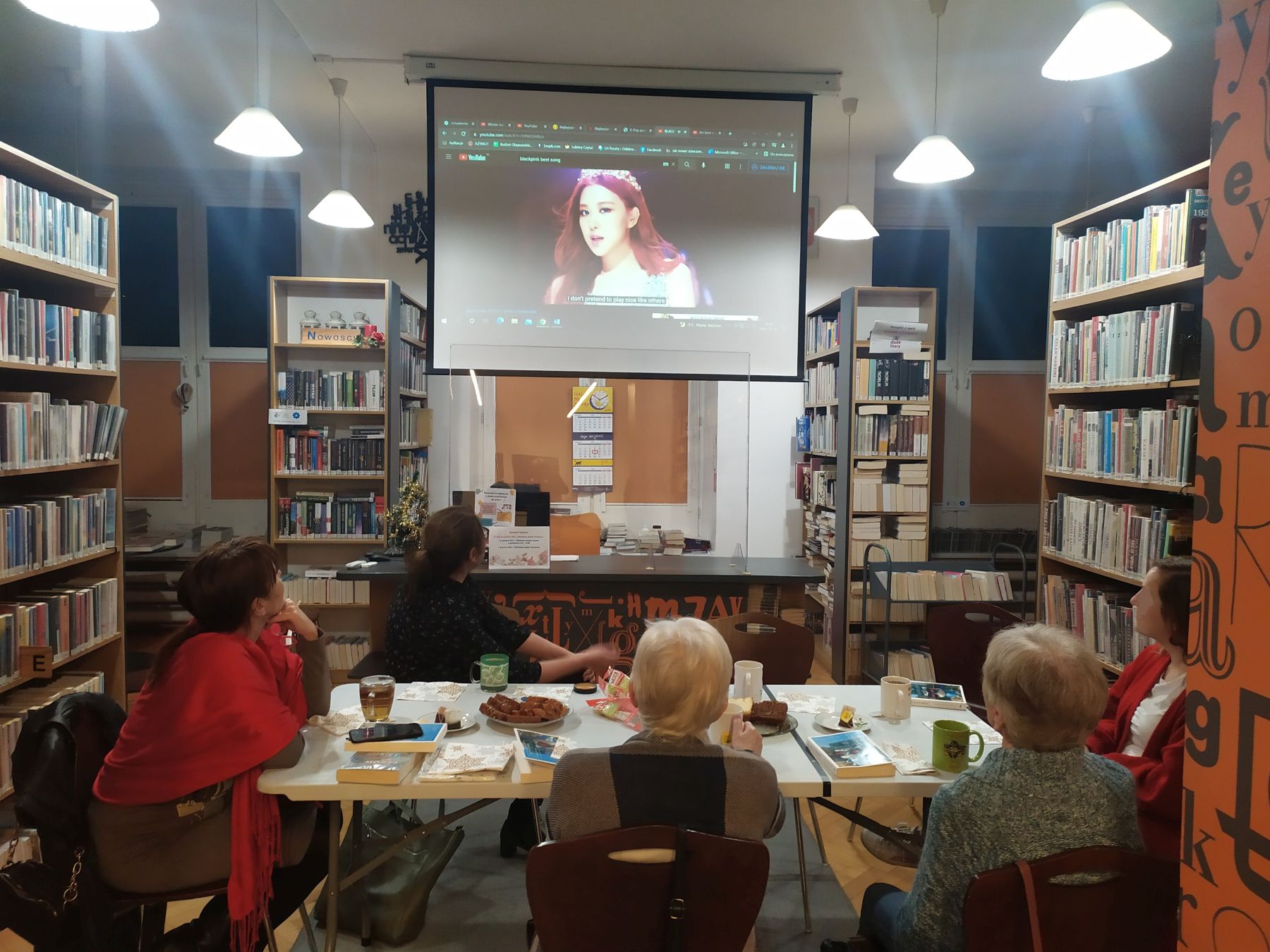 Członkinie Dyskusyjnego Klubu Książki podczas spotkania oglądają na wyświetlaczu fragment filmu.
