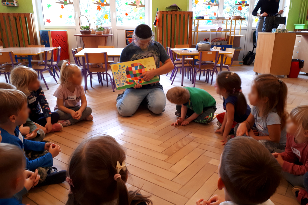 zdjecie przedstawiające lekcję biblioteczną prowadzoną przez bibliotekarzy i wolontariusza w przedszkolu 131 w ramach partnerstwa przedszkola i biblioteki