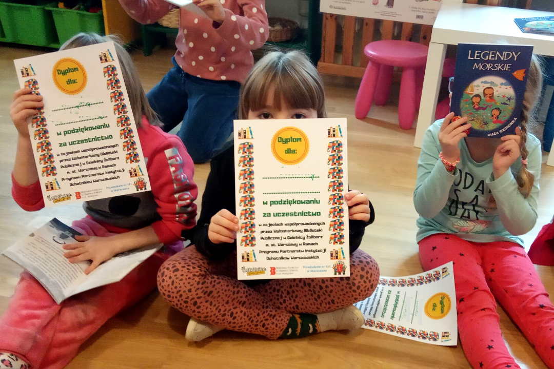 zdjecie przedstawiające lekcję biblioteczną prowadzoną przez bibliotekarzy i wolontariusza w przedszkolu 131 w ramach partnerstwa przedszkola i biblioteki