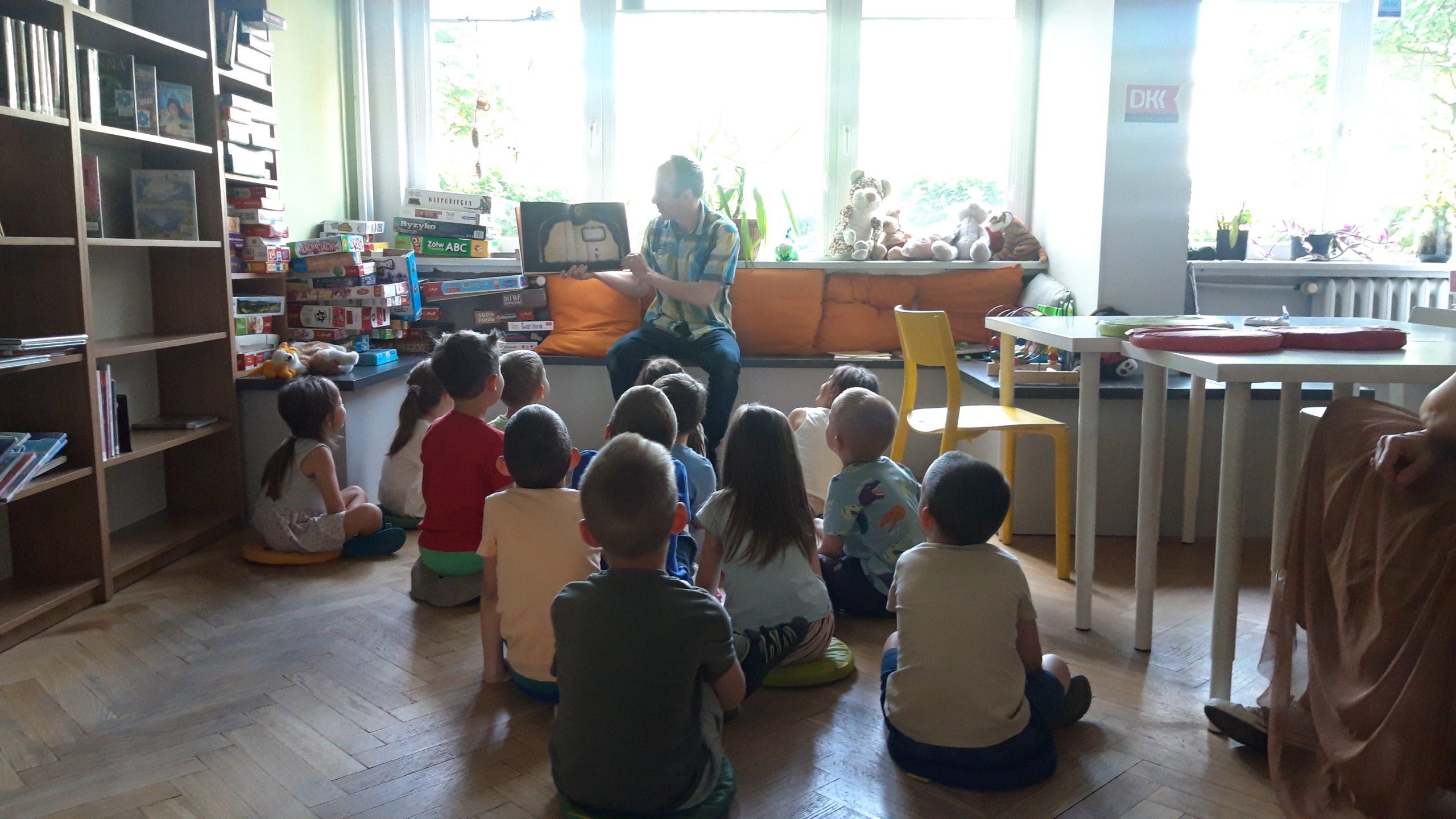 Dzieci słuchają czytanego przez bibliotekarza opowiadania.