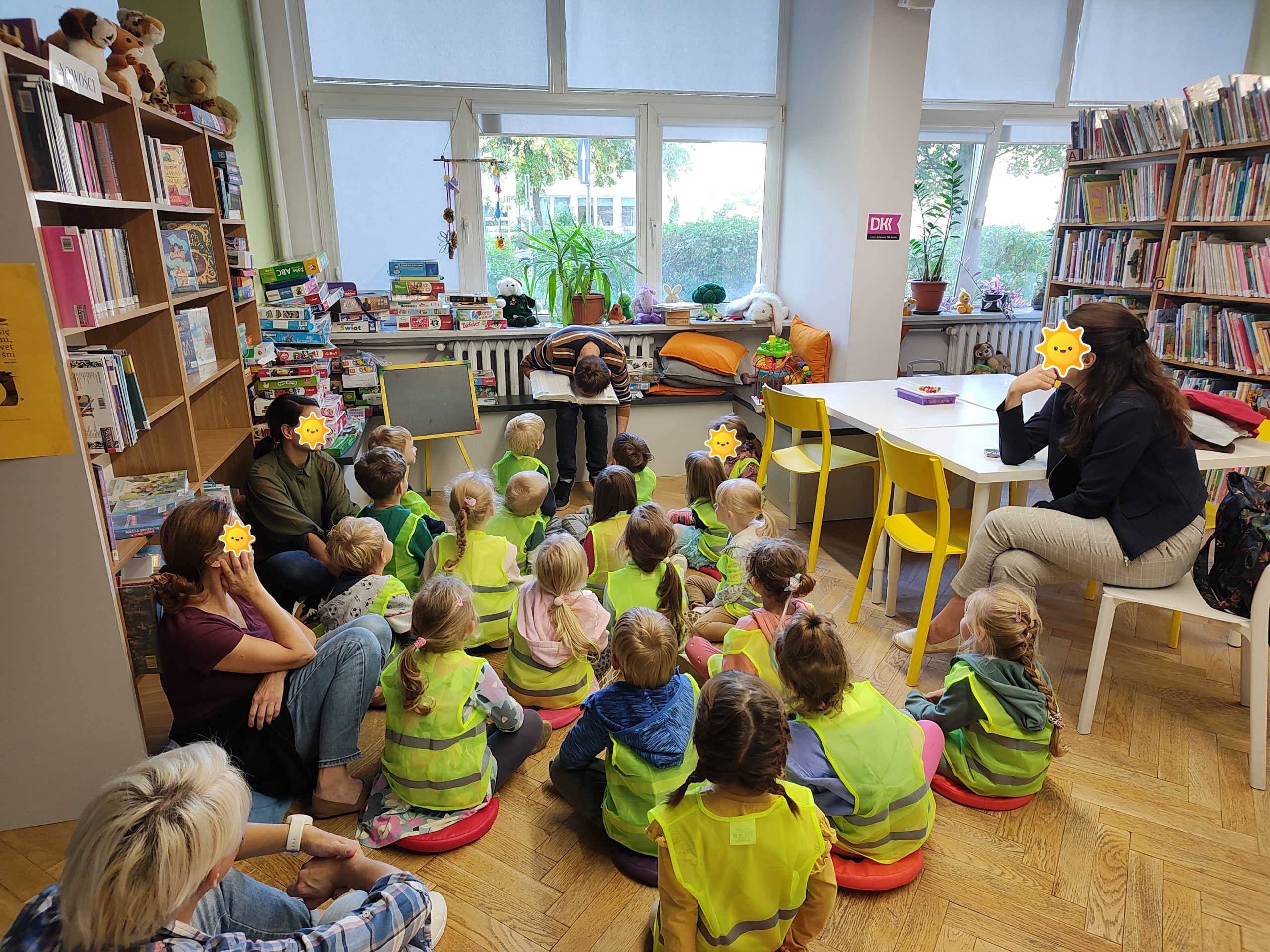 Przedszkolaki wraz z opiekunkami podczas jednego ze spotkań w bibliotece. Bibliotekarz wprowadził humorystyczny element czytania encyklopedii.