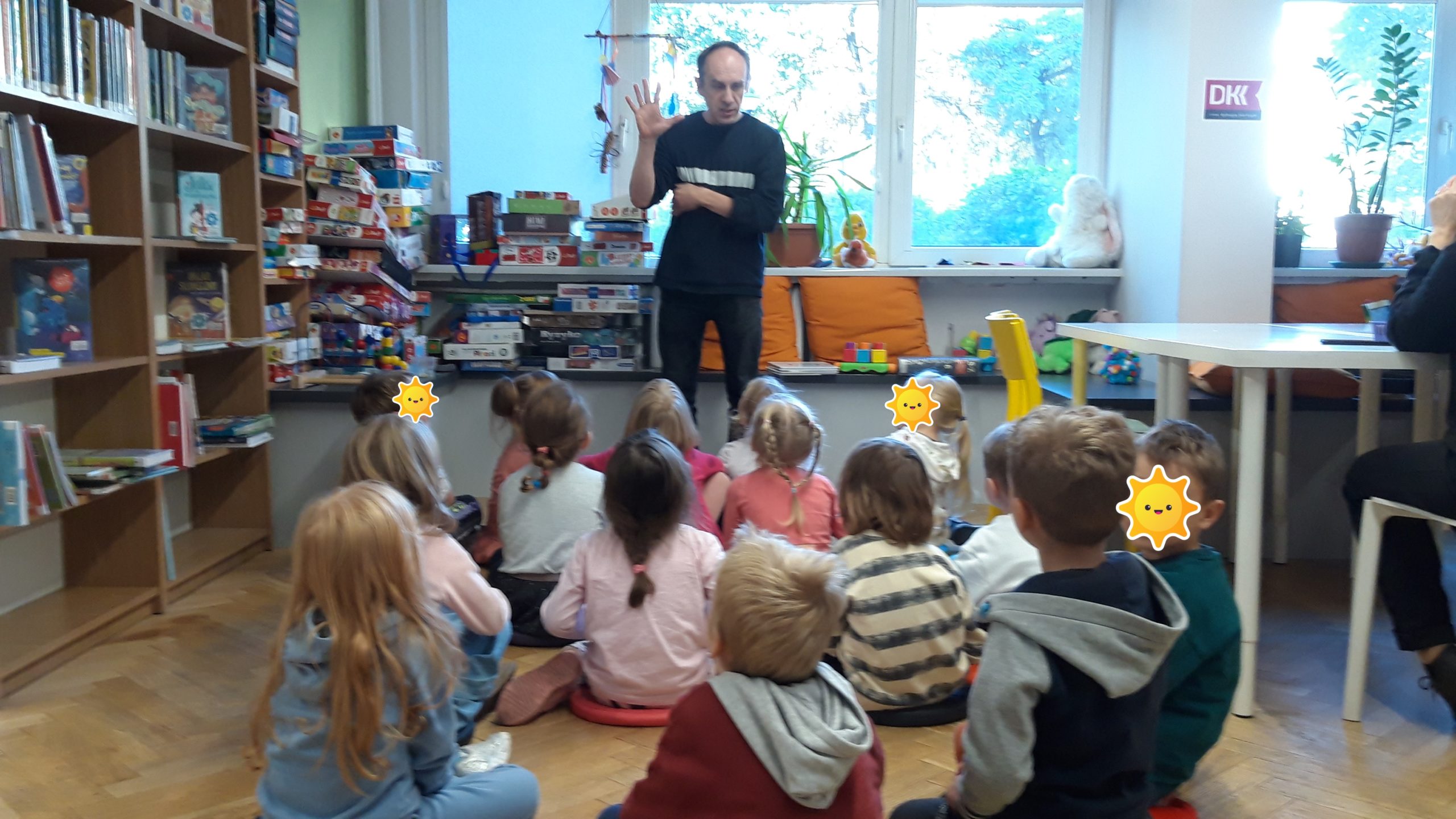 Przedszkolaki podczas rozmowy z bibliotekarzem, który pyta grupę o ilość wypożyczanych książek w bibliotece.