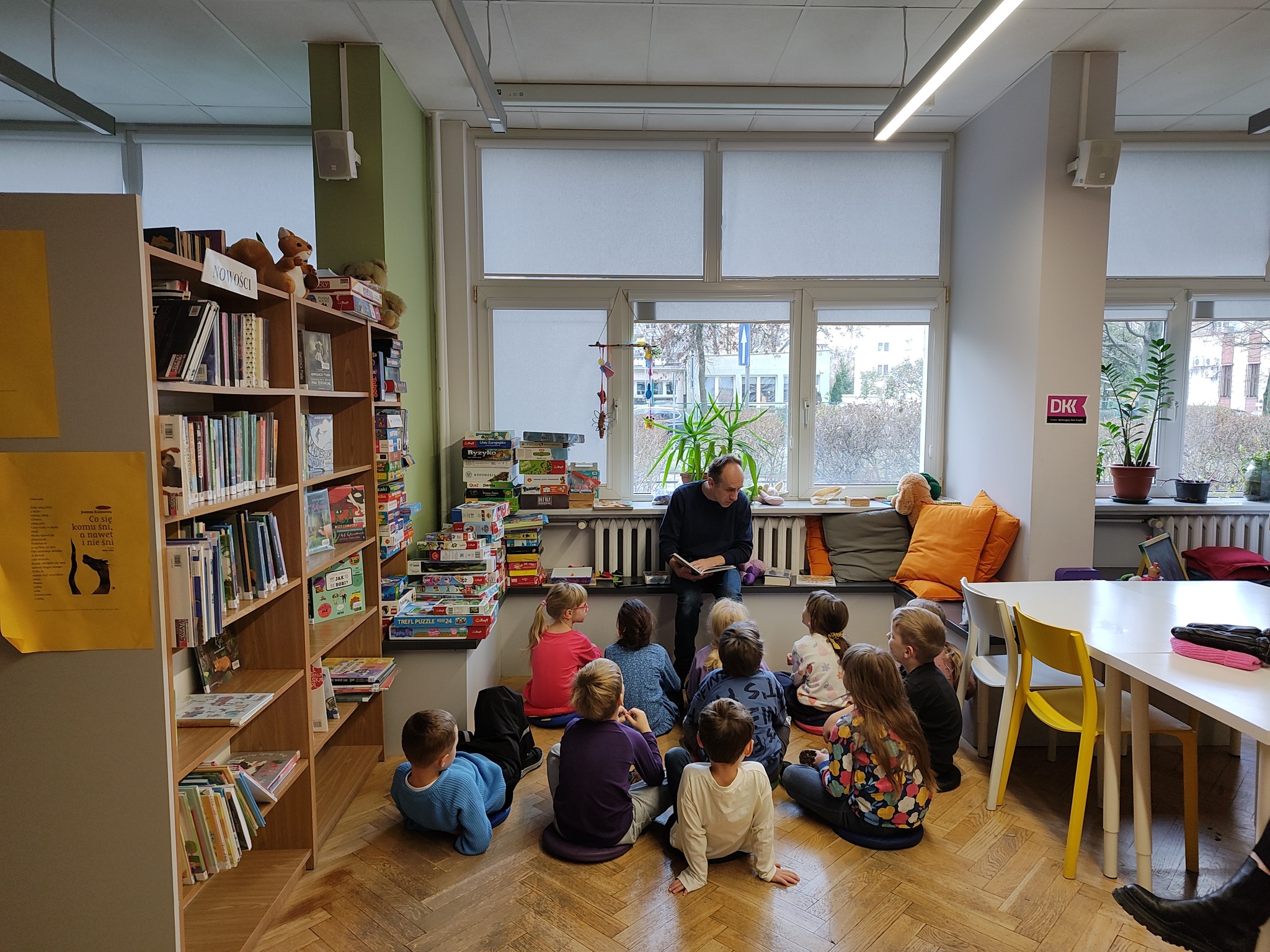 grafika wyróżniająca przedstawiająca grupę dzieci podczas rozmowy o książce z bibliotekarzem.