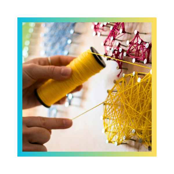 zdjęcie osoby wykonującej obrazek w technice string art, w kolorowej ramce