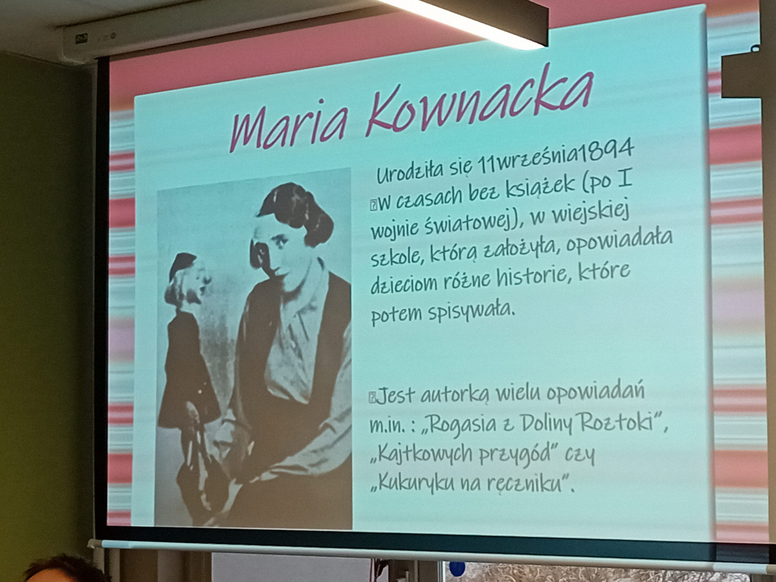 grafika wyróżniająca przedstawiająca ekran ze slajdem prezentacji o Marii Kownackiej. Na slajdzie widnieje czarno-białe zdjęcie autorki, która trzyma lalkę Plastusia. Obok zdjęcia widnieje krótki tekst o Kownackiej.