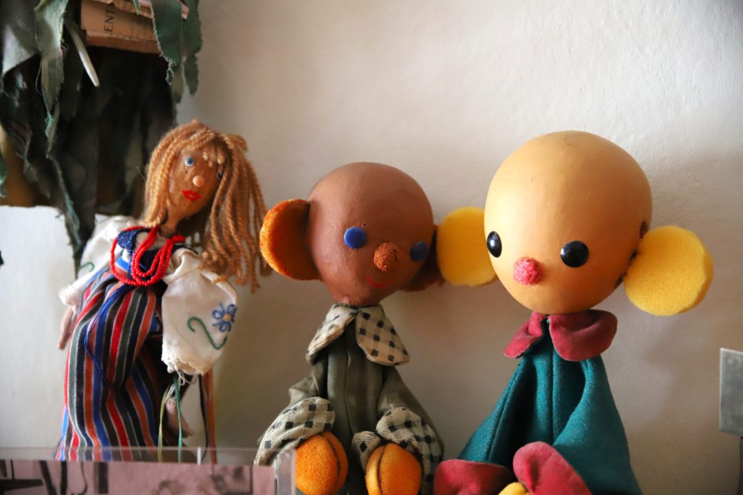 zdjęcie z wnętrza Muzeum Książki Dziecięcej lub inaczej Izby Pamięci Marii Kownackiej, która mieści się na warszawskim Żoliborzu przy ulicy Słowackiego 5/13 m. 74. plastelinowe figurki plastusiów na półce na tle białej ściany.