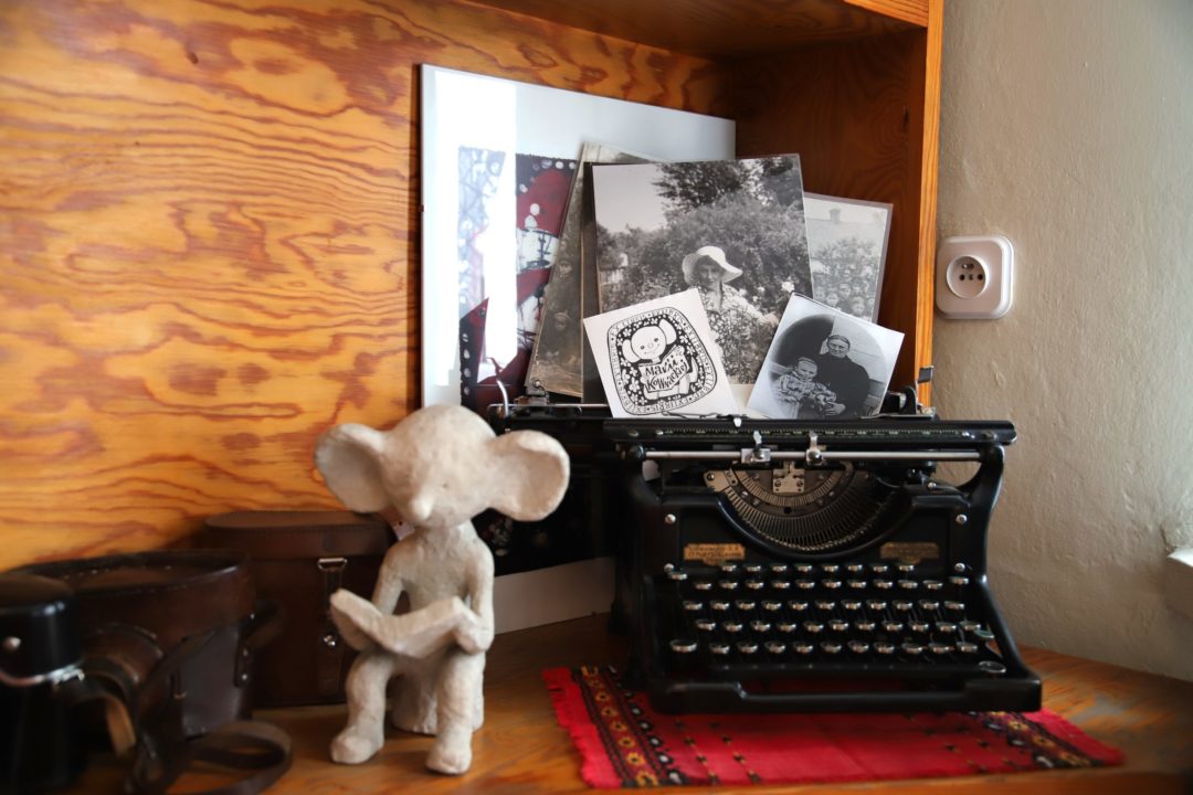 zdjęcie z wnętrza Muzeum Książki Dziecięcej lub inaczej Izby Pamięci Marii Kownackiej, która mieści się na warszawskim Żoliborzu przy ulicy Słowackiego 5/13 m. 74. zdjęcie maszyny do pisania z fotografiami marii kownackiej oraz glinianą figurką plastusia na półce