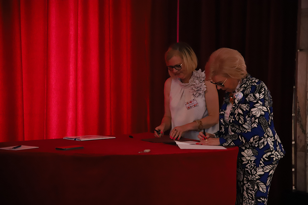 Zdjęcie z II Żoliborskiego Konkursu Recytatorskiego im. Joanny Kulmowej zorganizowanego przez Bibliotekę Publiczną w Dzielnicy Żoliborz, Społeczny Dom Kultury WSM oraz Fundację Joanny i Jana Kulmów. Dyrektor Biblioteki oraz Prezes Fundacji Joanny i Jana Kulmów podpisują wieloletnią wspópracę w głębi sceny Społecznego Domu Kultury.