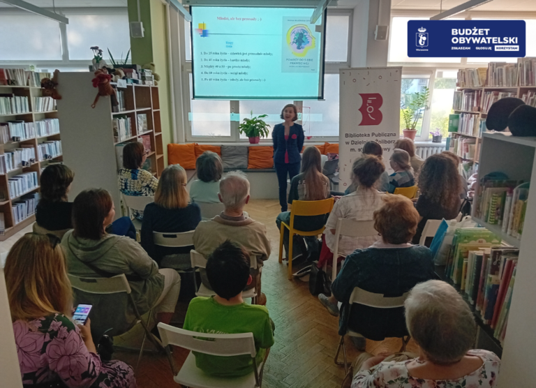 grafika przedstawiająca grupę osób w różnym wieku, która słucha wykładu dotyczącego treningu pamięci. Wykład prowadzi kobieta, która jest ubrana w granatowy strój. Za nią znajduje się ekran ze slajdami. W prawym górnym rogu widnieje granatowe logo Budżetu obywatelskiego.