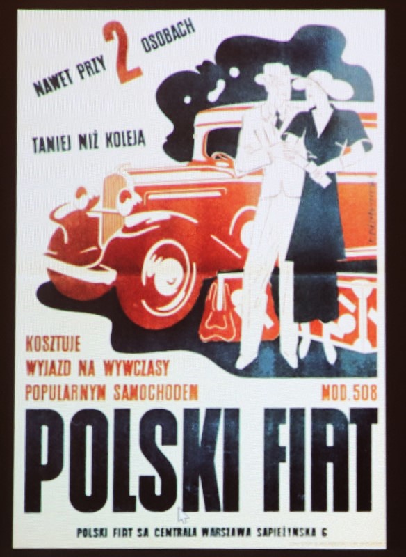 Zdjęcie z prelekcji "Motoryzacja Polska w Dwudziestoleciu Międzywojennym" we wnętrzu Wypożyczalni nr 16. Przedwojenny afisz z kobietą i mężczyzną oraz samochodem reklamujący zakup polskiego fiata. Widoczne napisy: Nawet przy 2 osobach taniej niż koleją kosztuje wyjazd na wywczasy popularnym samochodem mod. 508 polski fiat polski fiat sa centrala warszawa sapieżyńska 6