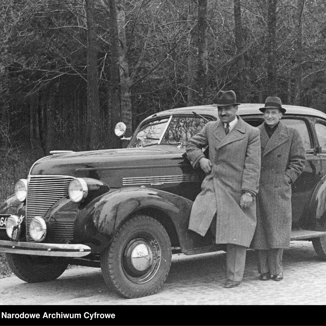 Fotografia z roku 1937, nieznany autor, Polscy kierowcy - mężczyźni Mieczysław Rządkowski i Aleksander Mazurek stoją przy samochodzie Chevrolet przed wyruszeniem do Trypolisu. Napis w dolnym lewym rogu: Narodowe Archiwum Cyfrowe.