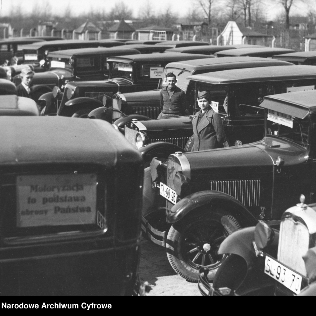 Fotografia z lat 1930-1939, autor zdjęcia Czesław Datka, Grupa właścicieli taksówek przy pojazdach. Po lewej widoczna tabliczka lub karta przymocowana na szybie samochodu z hasłem: "Motoryzacja to podstawa obrony Państwa". Napis w dolnym lewym rogu: Narodowe Archiwum Cyfrowe.