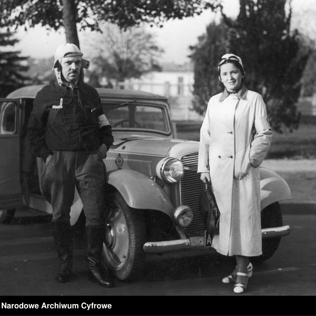 Fotografia z lat 1930-1939, autor zdjęcia nieznany, dwie postacie Helena Howorko wraz z mężem przy samochodzie Adler -Tryumf-Junior na tle drzew i budynków. Napis w dolnym lewym rogu: Narodowe Archiwum Cyfrowe.