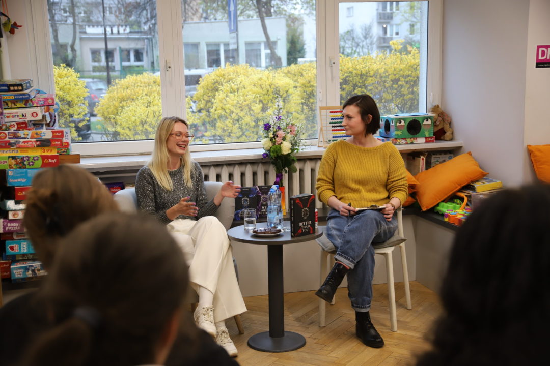 zdjecie ze spotkania autorskiego z Ann Holly we wnętrzu wypożyczalni nr 138. autorka rozmawia z osobą prowadzącą.