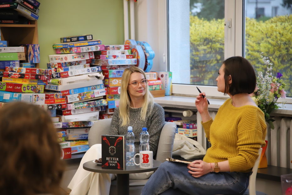 zdjecie ze spotkania autorskiego z Ann Holly we wnętrzu wypożyczalni nr 138. autorka rozmawia z osobą prowadzącą.