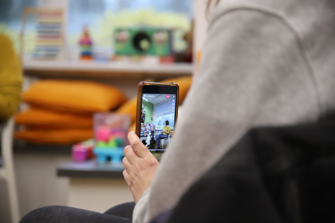 zdjecie ze spotkania autorskiego z Ann Holly we wnętrzu wypożyczalni nr 138. osoba trzyma telefon komórkowy i nagrywa relację ze spotkania na żywo.