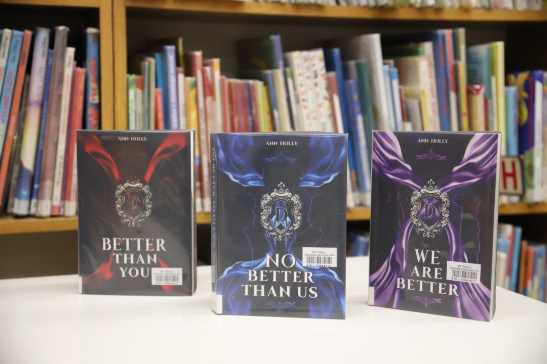 zdjecie ze spotkania autorskiego z Ann Holly we wnętrzu wypożyczalni nr 138. trzy egzemplarze książek autorki: better than you, no better than us, we are better