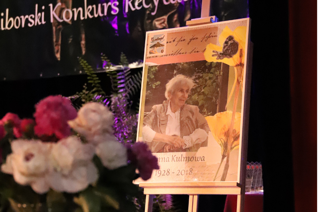 Zdjęcie z III Żoliborskiego Konkursu Recytatorskiego im. Joanny Kulmowej zorganizowanego przez Bibliotekę Publiczną w Dzielnicy Żoliborz, Społeczny Dom Kultury WSM oraz Fundację Joanny i Jana Kulmów. Portret Joanny Kulmowej na sztaludze.