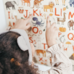 Dziecko zwrócone twarzą do tablicy, na literki na której znajdują duże i małe literki oraz zwierzęta.