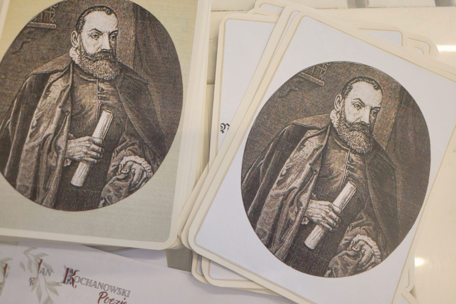 Na stole karty przedstawiające grafikę mężczyzny w stroju renesansowym, niżej kartka, w rogu której tekst Jan Kochanowski Poezje