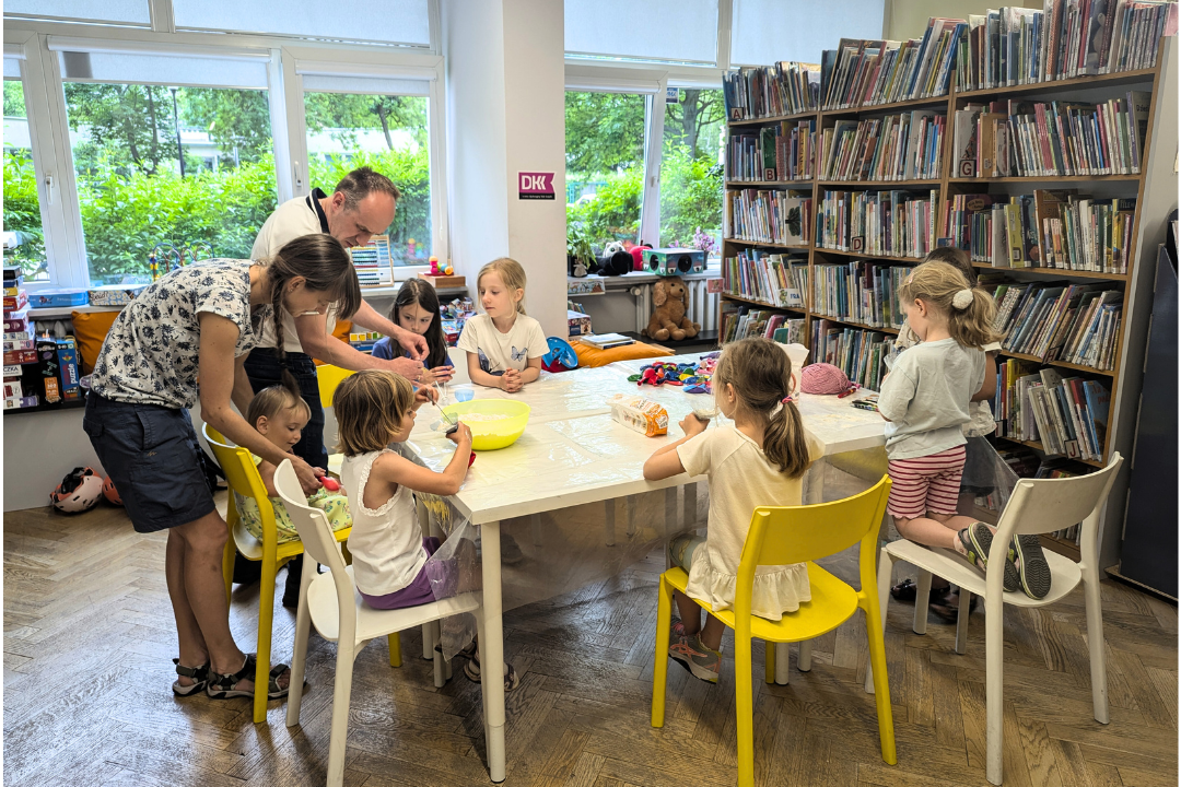 zdjęcie dzieci przy stole w bibliotece bawiących się mąką