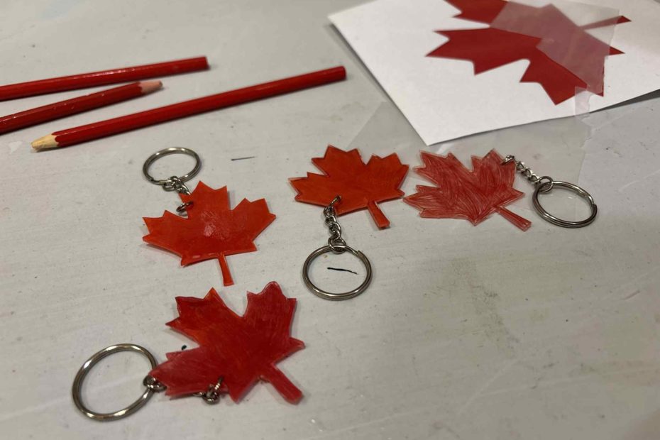 grafika przedstawiająca wykonane breloczki na spotkaniu Klubu Podróżników Neli Małej Reporterki. Są to czerwone liście klonu zrobione z termokurczliwej folii.