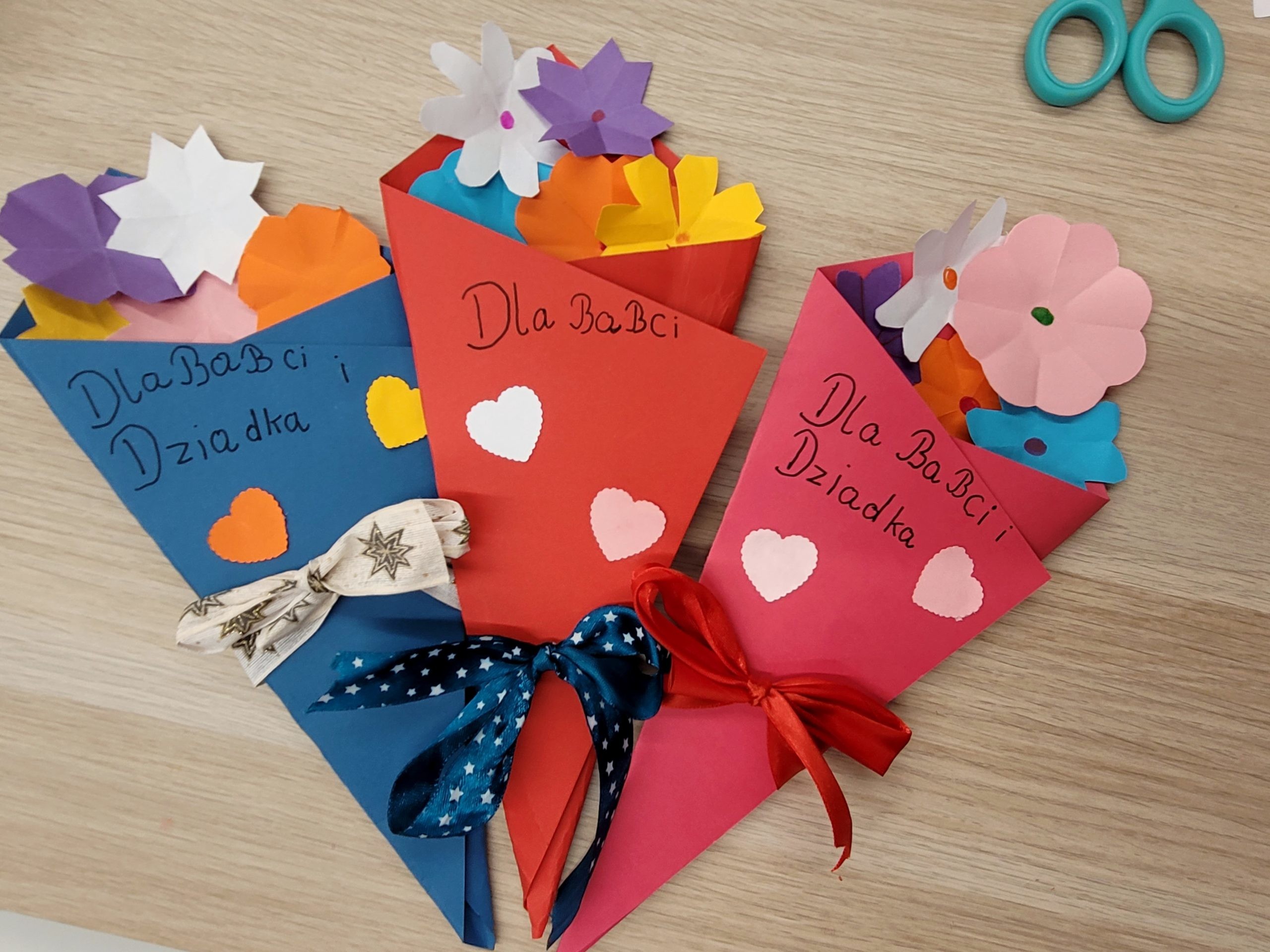 Trzy papierowe bukiety ozdobione kolorowymi sercami i wstążkami. Na nich ręczne napisy: "Dla Babci i Dziadka", "dla Babci", "dla Babci i Dziadka".