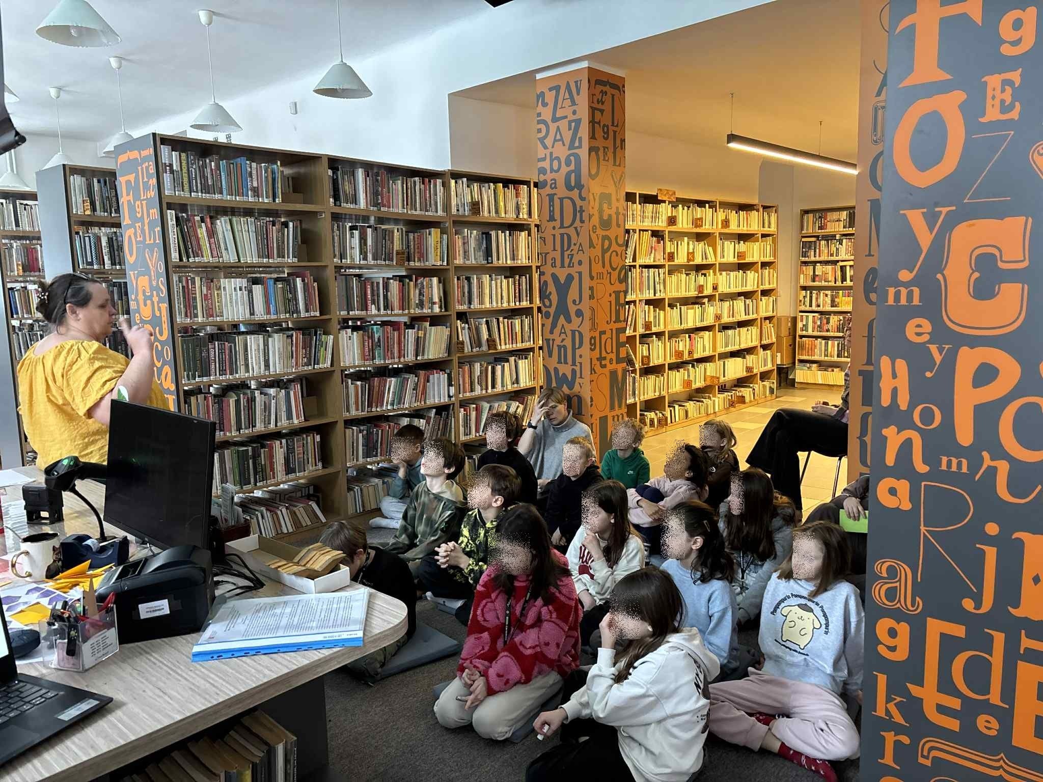 zdjęcie przedstawia grupę szkolną dzieci, które słuchają prelekcji o Brazylii.